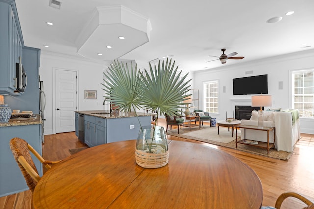 dining room featuring crown molding, light wood-type flooring, sink, and ceiling fan