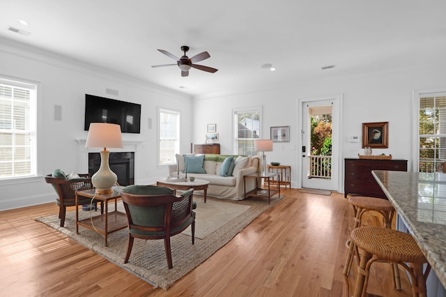 living room featuring crown molding, light hardwood / wood-style floors, a healthy amount of sunlight, and ceiling fan