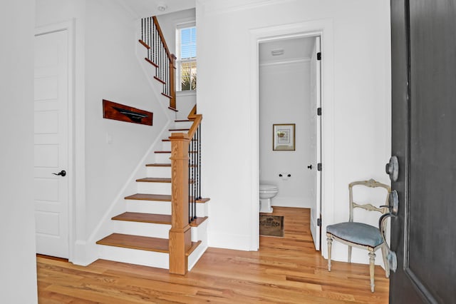 staircase with ornamental molding and wood-type flooring