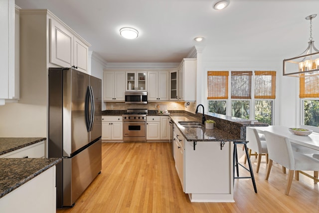 kitchen with a sink, glass insert cabinets, appliances with stainless steel finishes, a kitchen bar, and tasteful backsplash