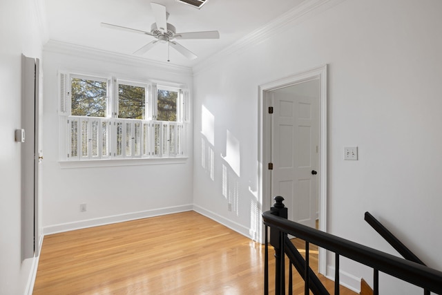 interior space with ceiling fan, baseboards, light wood finished floors, and ornamental molding