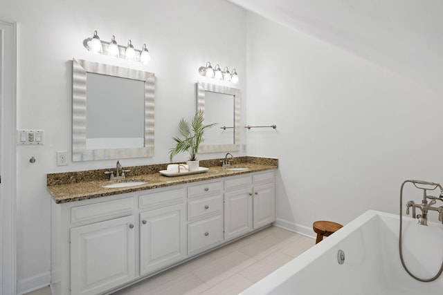 bathroom with a freestanding bath, double vanity, baseboards, and a sink