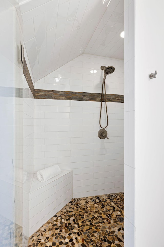 full bathroom featuring tiled shower and lofted ceiling