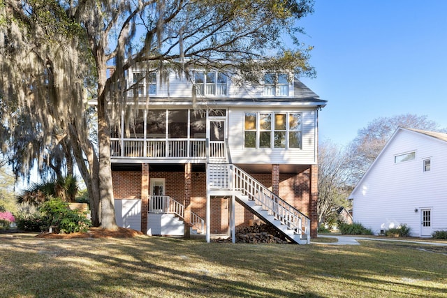 back of house featuring a yard, brick siding, stairway, and a sunroom