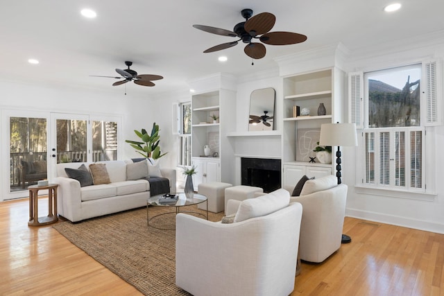 living area featuring recessed lighting, light wood-style floors, ornamental molding, and a fireplace