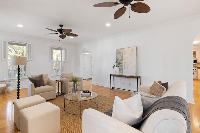 living area with ornamental molding, recessed lighting, arched walkways, light wood-style floors, and baseboards