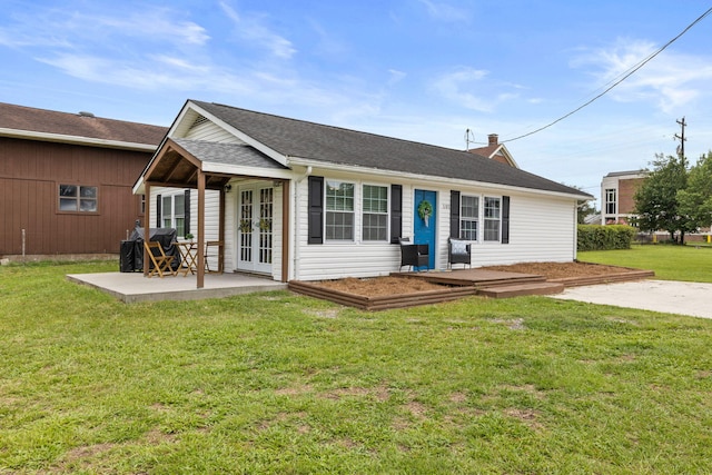 rear view of property with a lawn, a patio area, and french doors