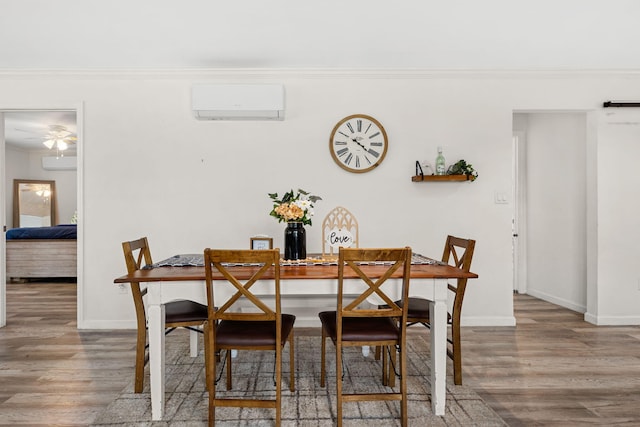 dining space with a wall mounted air conditioner, wood-type flooring, and ornamental molding