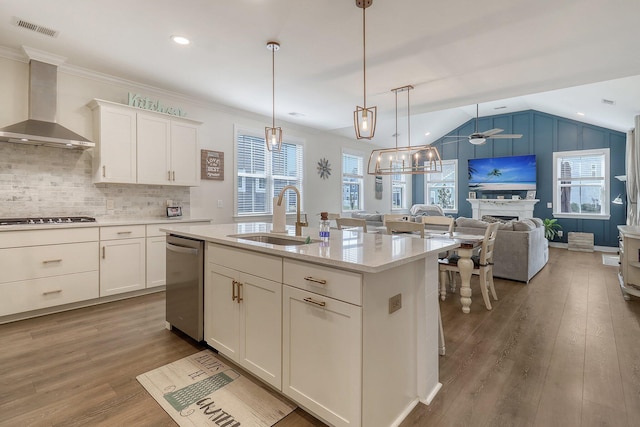 kitchen featuring hardwood / wood-style floors, stainless steel appliances, hanging light fixtures, wall chimney exhaust hood, and sink