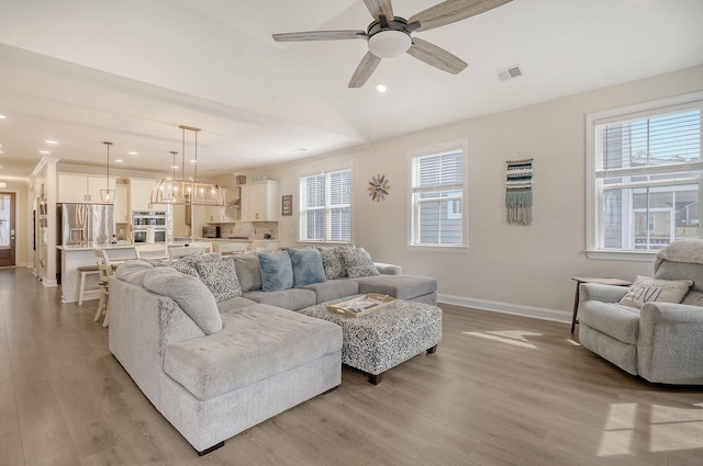 living room with ceiling fan, light hardwood / wood-style floors, and a wealth of natural light