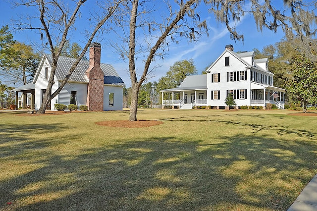 rear view of property featuring a yard and covered porch