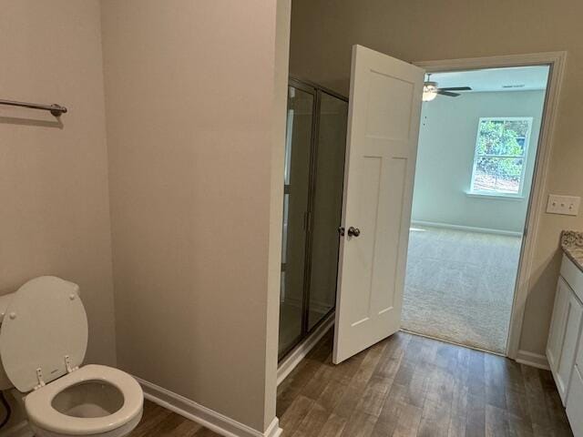 bathroom featuring vanity, ceiling fan, hardwood / wood-style flooring, toilet, and a shower with shower door