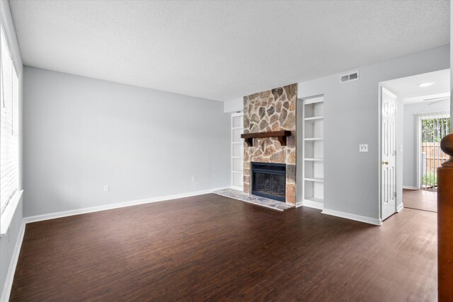 7813 Sandida Ct, North Charleston, SC 29418 - unfurnished living room featuring built in shelves, baseboards, dark wood-style flooring, a fireplace, and a textured ceiling