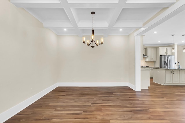 unfurnished dining area featuring coffered ceiling, a notable chandelier, beam ceiling, and dark wood-type flooring