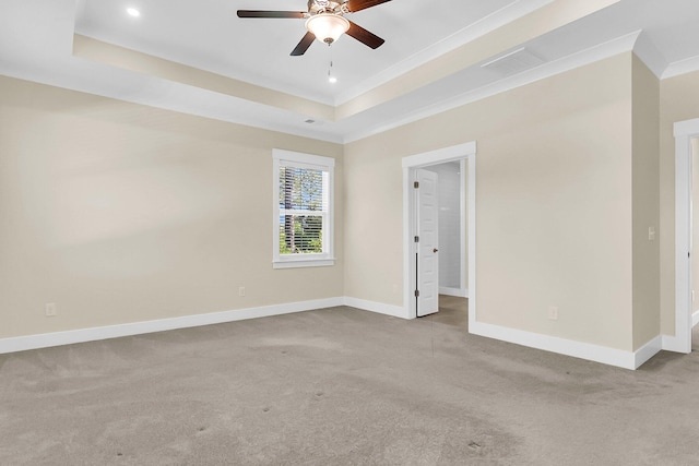 spare room with crown molding, ceiling fan, a tray ceiling, and light carpet