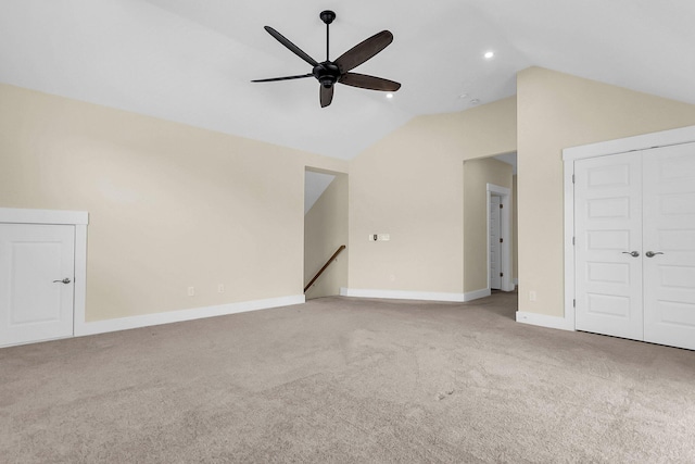 unfurnished living room with ceiling fan, light colored carpet, and vaulted ceiling