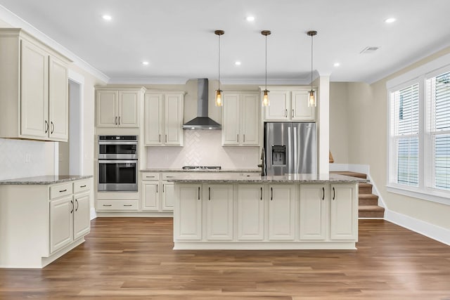 kitchen featuring hanging light fixtures, stainless steel appliances, a center island, light stone counters, and wall chimney exhaust hood