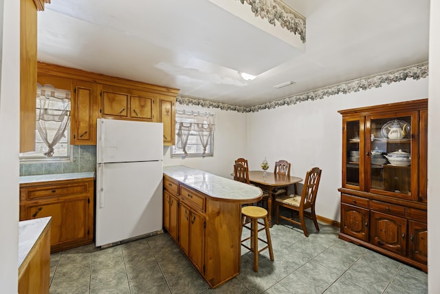 kitchen featuring white fridge, plenty of natural light, kitchen peninsula, and a kitchen bar