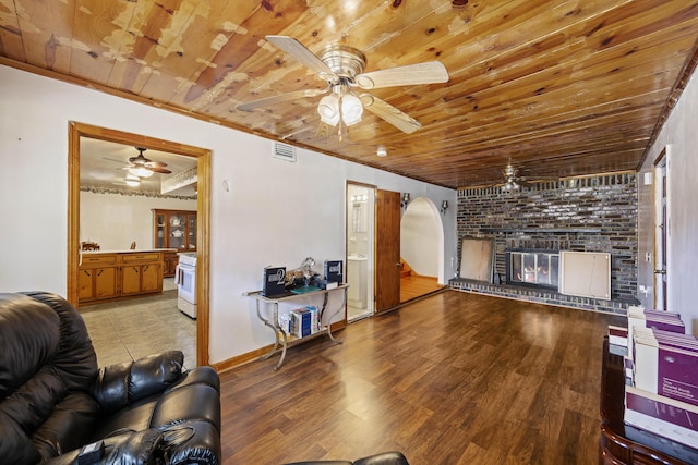 living room with wooden ceiling, a brick fireplace, and light hardwood / wood-style flooring