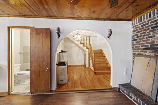 stairway with hardwood / wood-style flooring, a notable chandelier, crown molding, and wood ceiling