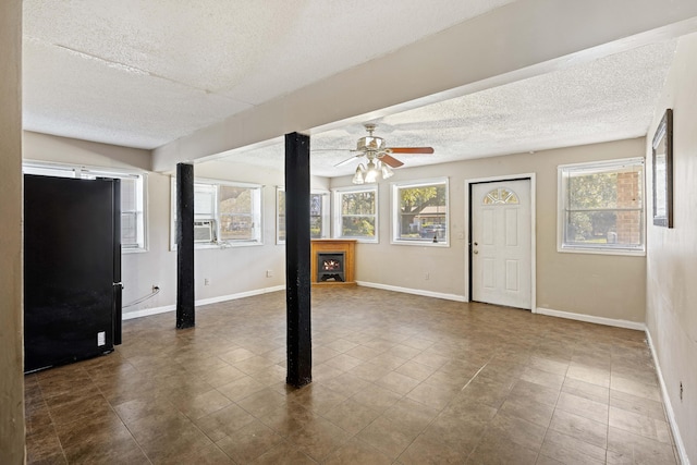 interior space with cooling unit, a textured ceiling, and ceiling fan