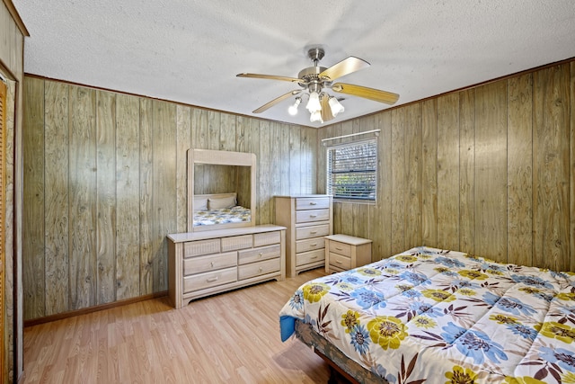 bedroom with wooden walls, a textured ceiling, ceiling fan, and light hardwood / wood-style flooring