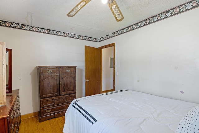 bedroom with ceiling fan, light wood-type flooring, and a textured ceiling