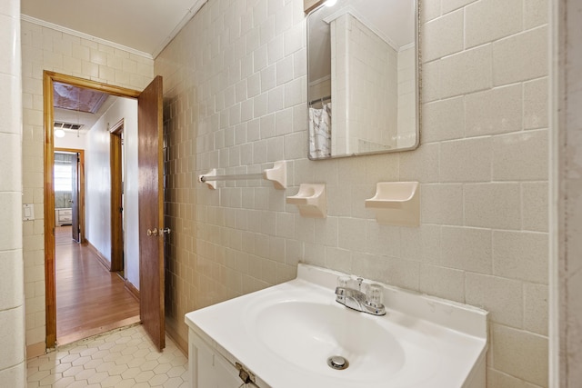 bathroom with tile patterned floors, vanity, tile walls, and crown molding