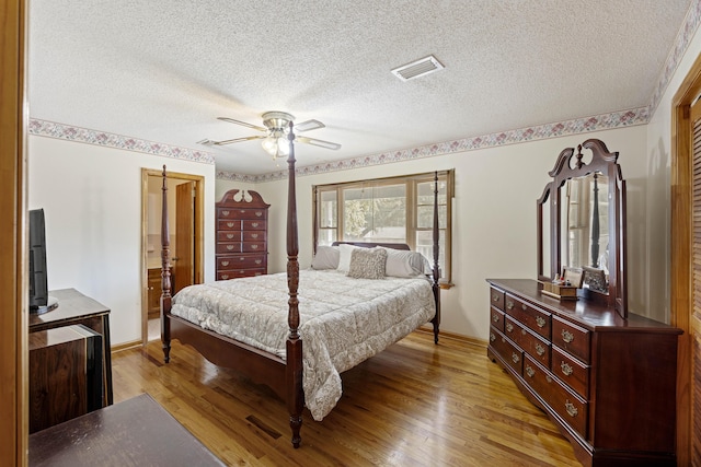 bedroom featuring ceiling fan, light hardwood / wood-style flooring, and a textured ceiling