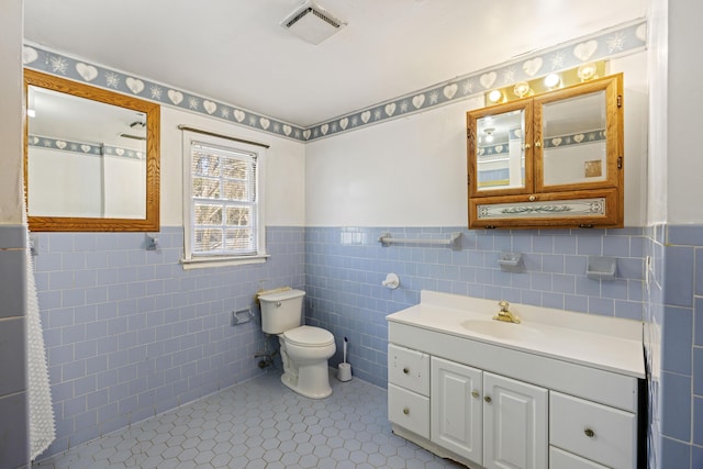 bathroom with tile walls, vanity, tile patterned floors, and toilet