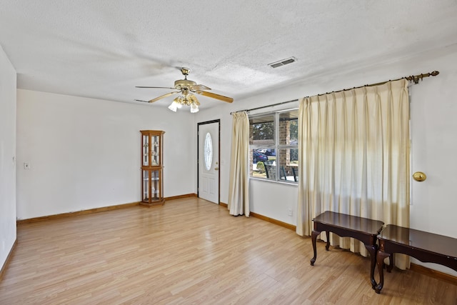 interior space featuring light wood-type flooring, ceiling fan, and a textured ceiling