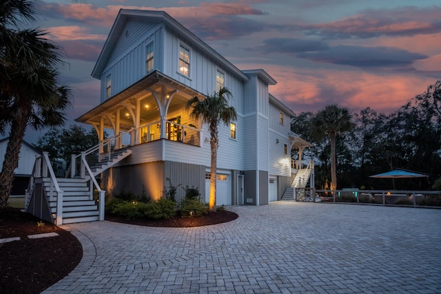 view of front of house with a garage, decorative driveway, stairs, and board and batten siding