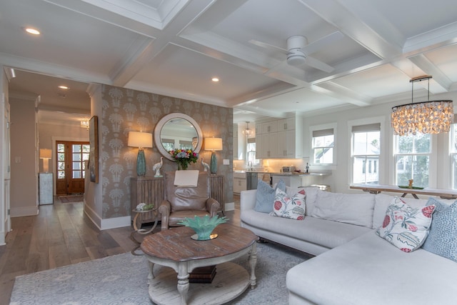 living area featuring wallpapered walls, baseboards, coffered ceiling, dark wood finished floors, and beamed ceiling