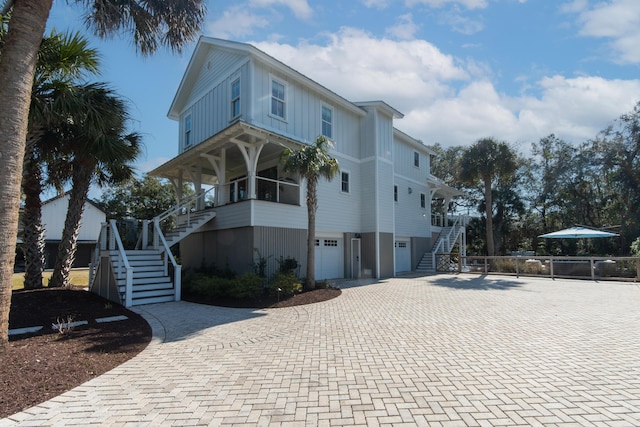 coastal inspired home featuring board and batten siding, decorative driveway, stairway, and a garage