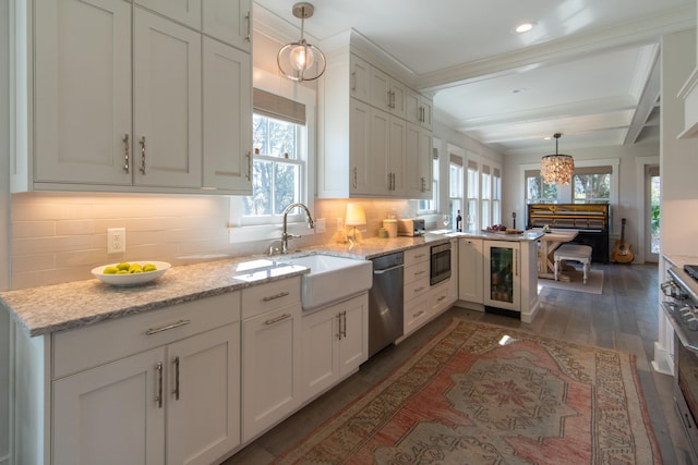 kitchen with a peninsula, hanging light fixtures, a sink, and appliances with stainless steel finishes