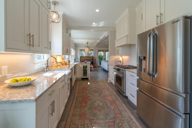 kitchen featuring light stone counters, high end appliances, white cabinets, and pendant lighting