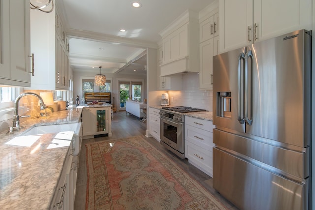 kitchen with light stone counters, dark wood-style flooring, a sink, high quality appliances, and white cabinets