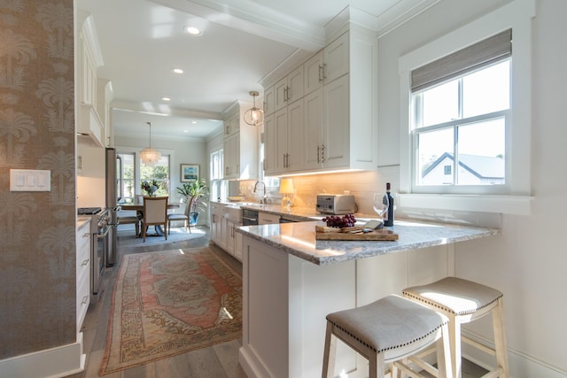 kitchen with white cabinets, light stone counters, high end range, a kitchen breakfast bar, and pendant lighting