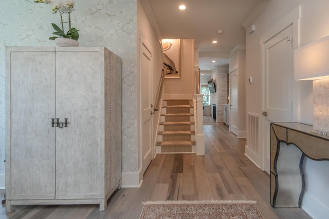 foyer entrance with recessed lighting, stairs, wallpapered walls, light wood finished floors, and crown molding