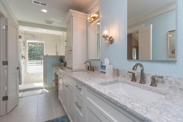 bathroom with double vanity, a sink, visible vents, and wallpapered walls