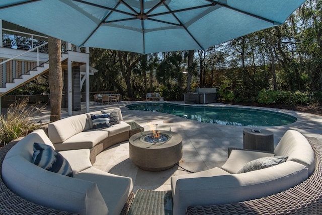 pool with a patio area, stairs, and an outdoor living space with a fire pit