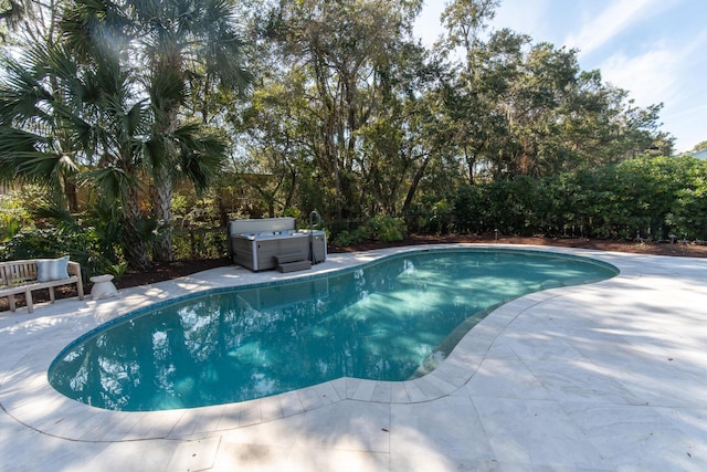 pool with a patio area and a hot tub