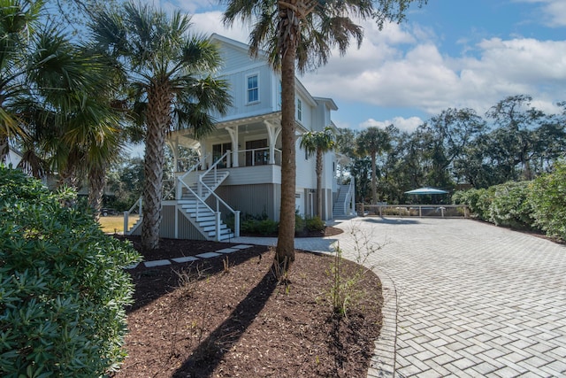 view of front of property featuring decorative driveway, covered porch, and stairs