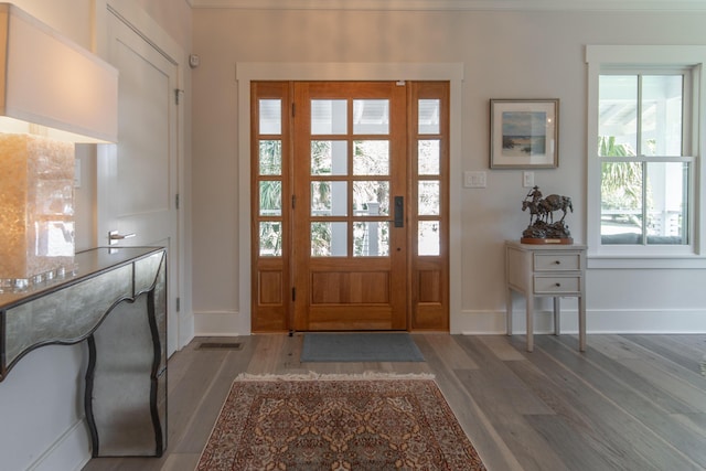 foyer entrance featuring visible vents, baseboards, and wood finished floors