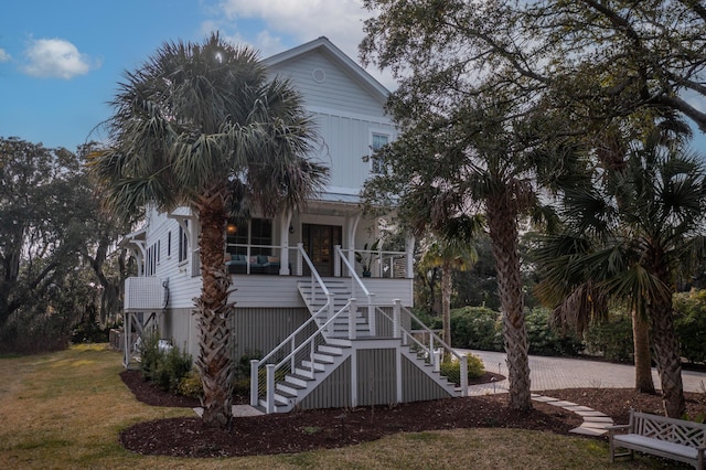 coastal inspired home with covered porch, french doors, stairway, and a front yard