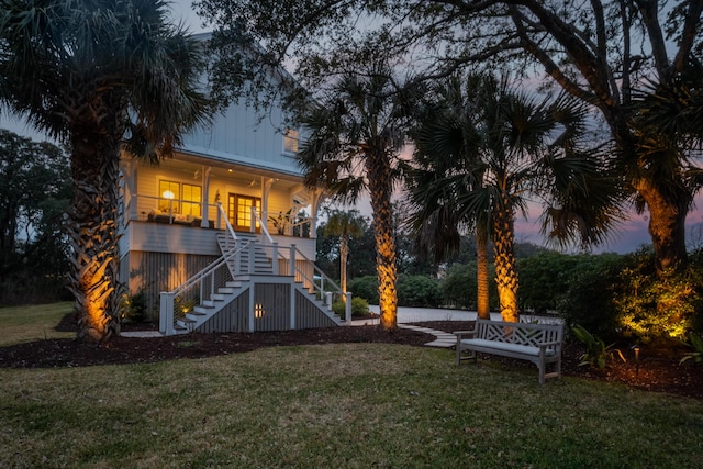 back of house with stairs and a lawn