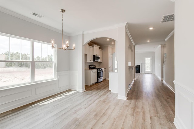 kitchen with light hardwood / wood-style flooring, appliances with stainless steel finishes, hanging light fixtures, white cabinets, and a chandelier