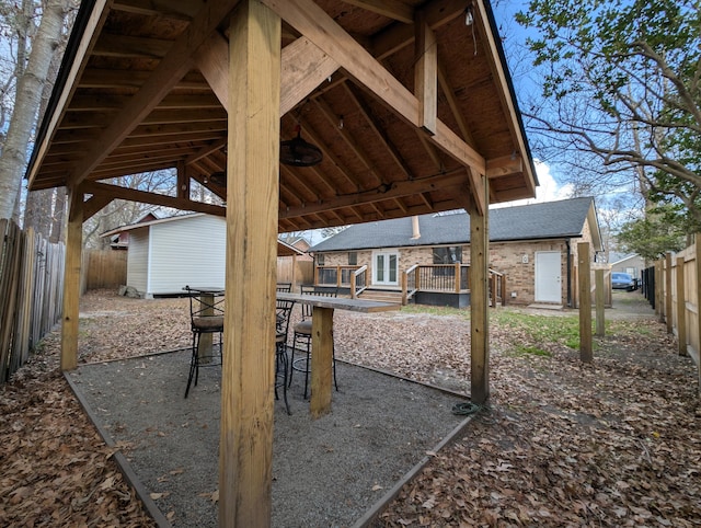 view of patio with a wooden deck, a storage unit, and an outdoor bar