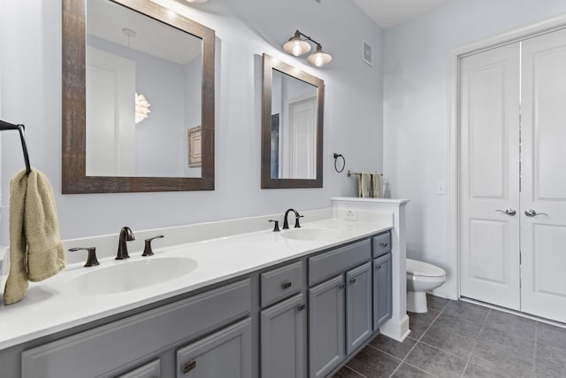 bathroom featuring double vanity, a sink, tile patterned flooring, and toilet