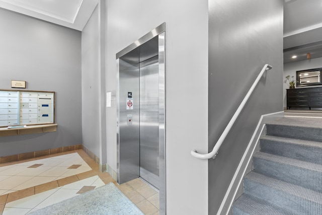 staircase featuring tile patterned floors, baseboards, elevator, and mail area